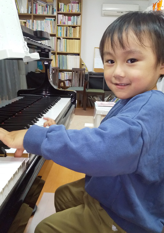 ピアノを弾きながら得意げにこちらを見る男の子の写真